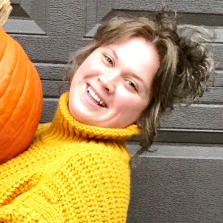 Haley leaning back and smiling while holding a pumpkin