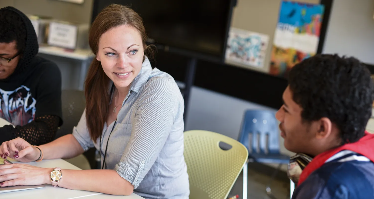 Woman at table talking with student 