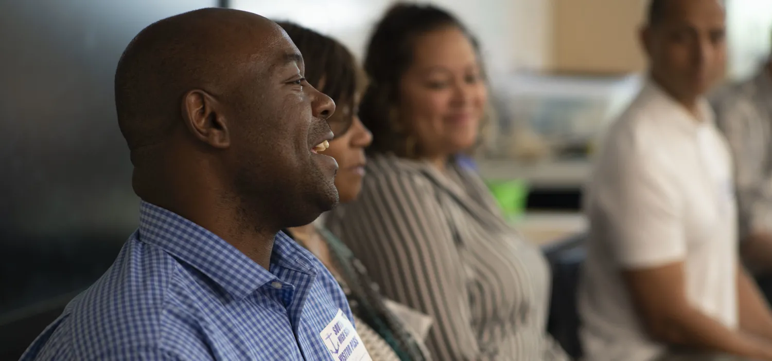 Four people in classroom talking with students 