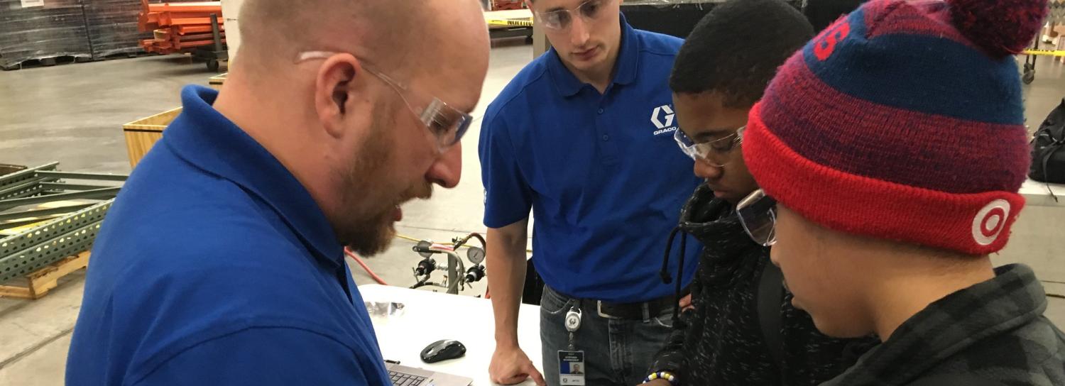 Adults demonstrate mechnical tools to students at Graco 