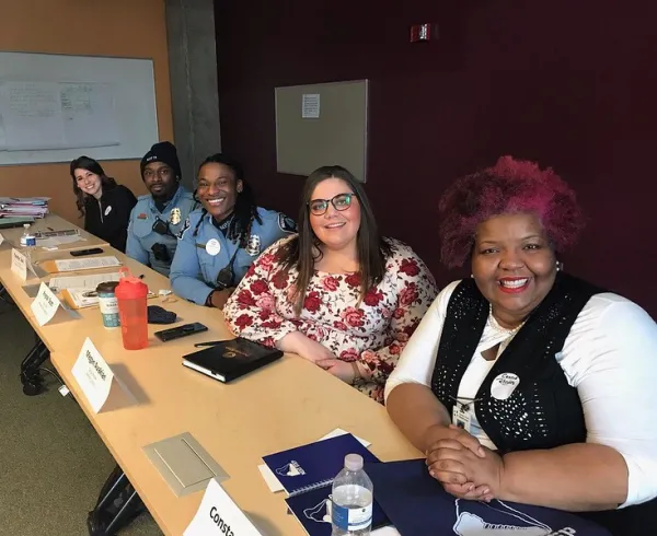 Four adults sitting at long table in classroom 