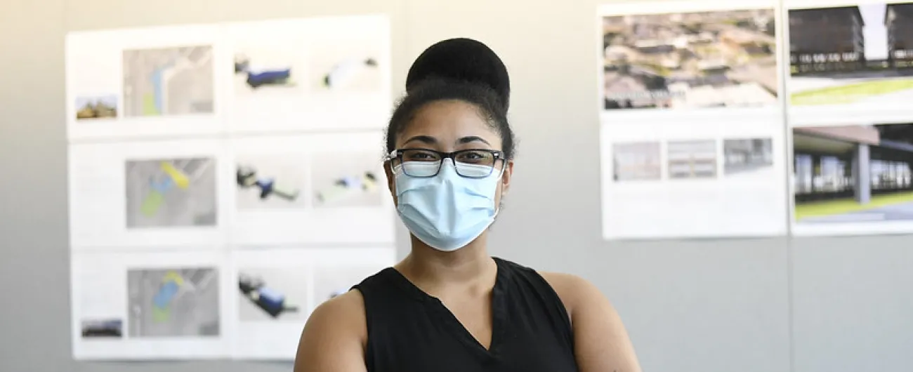 Woman standing with crossed arms in front of wall with architecture documents