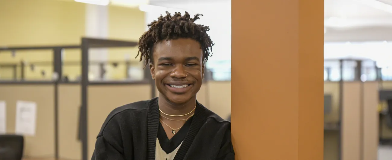 Intern leaning against pole in office 