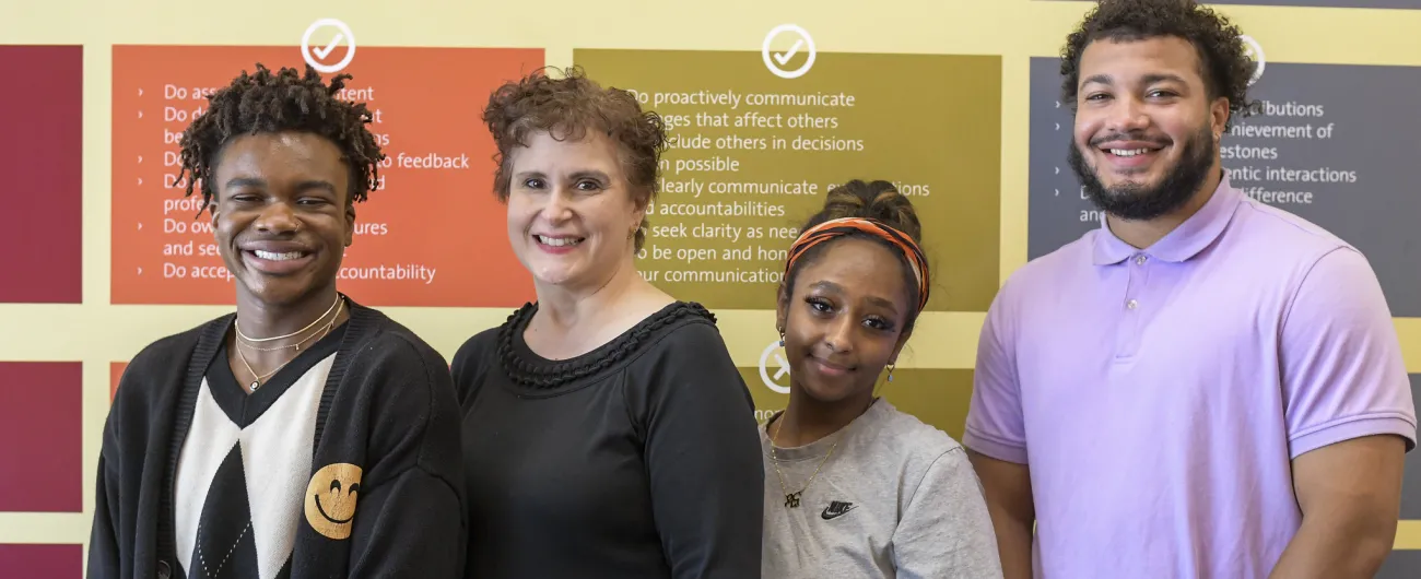 Interns and supervisor standing in front of office signs