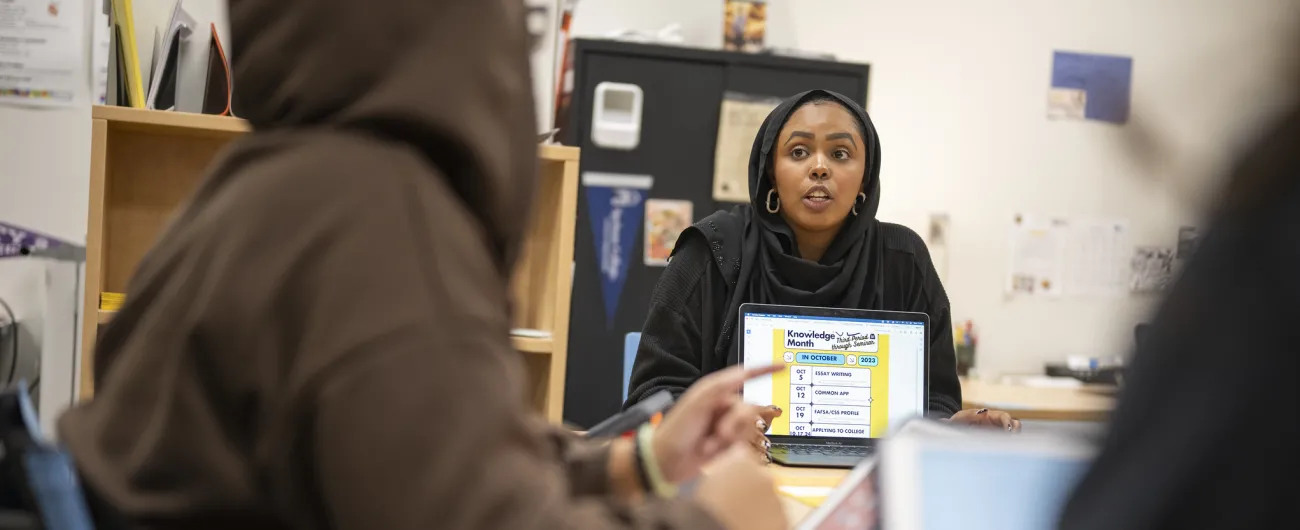 Aisha talking with students at table