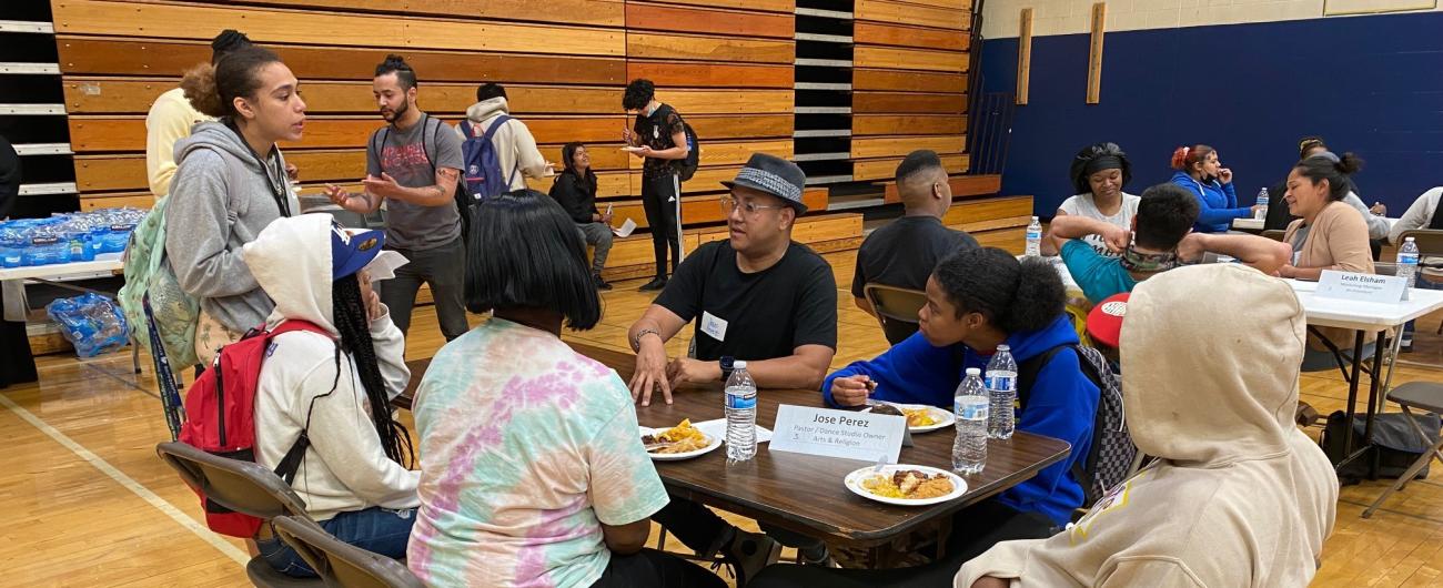 Pastor and artist talking with students in a school gym