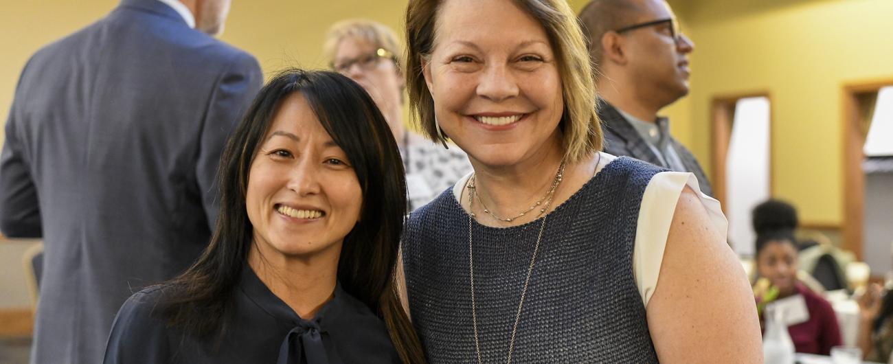 Two women at event looking at camera and smiling 