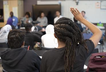 Student in classroom raising her hand 
